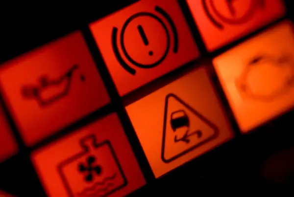 Close-up of a car dashboard with red and orange warning lights lit, including oil pressure, brake, coolant temperature, and traction control symbols.